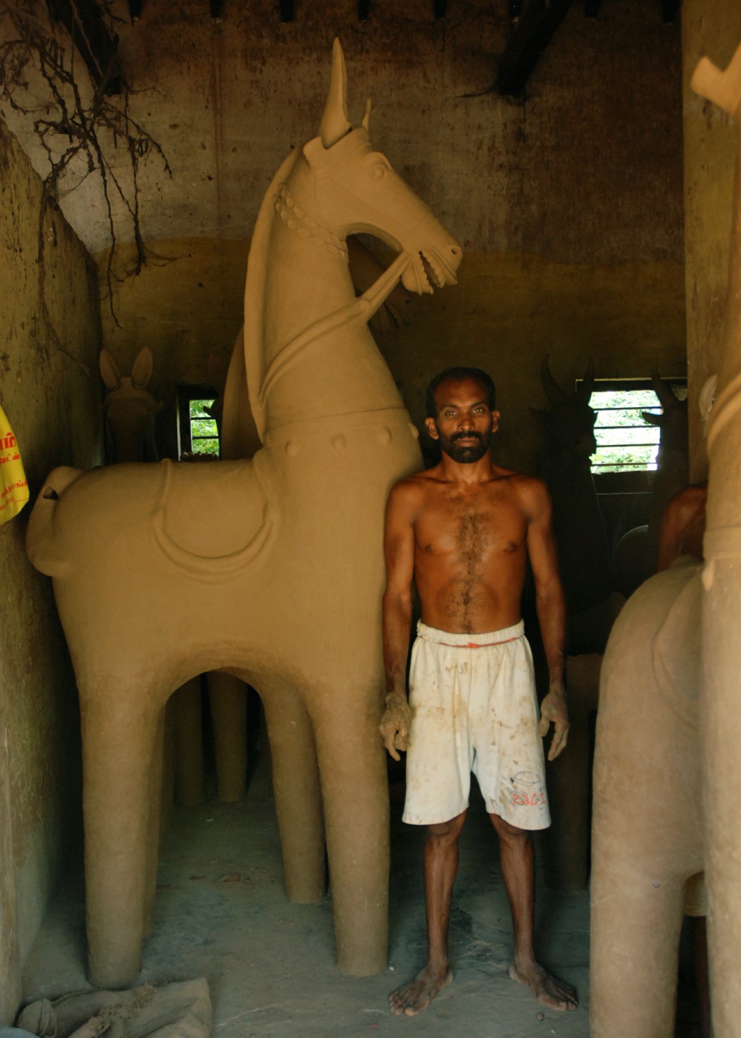 <span style="font-weight:normal;">Jaganathan is the head potter for the festival at Alianeley. The <i>ure-kuthirai</i> (village horse) he has just finished modelling for the annual festival, towers above him in the shelter of his workshop. The horse will dry for more than a week before Jaganathan brings it into the oven to be fired.</span>