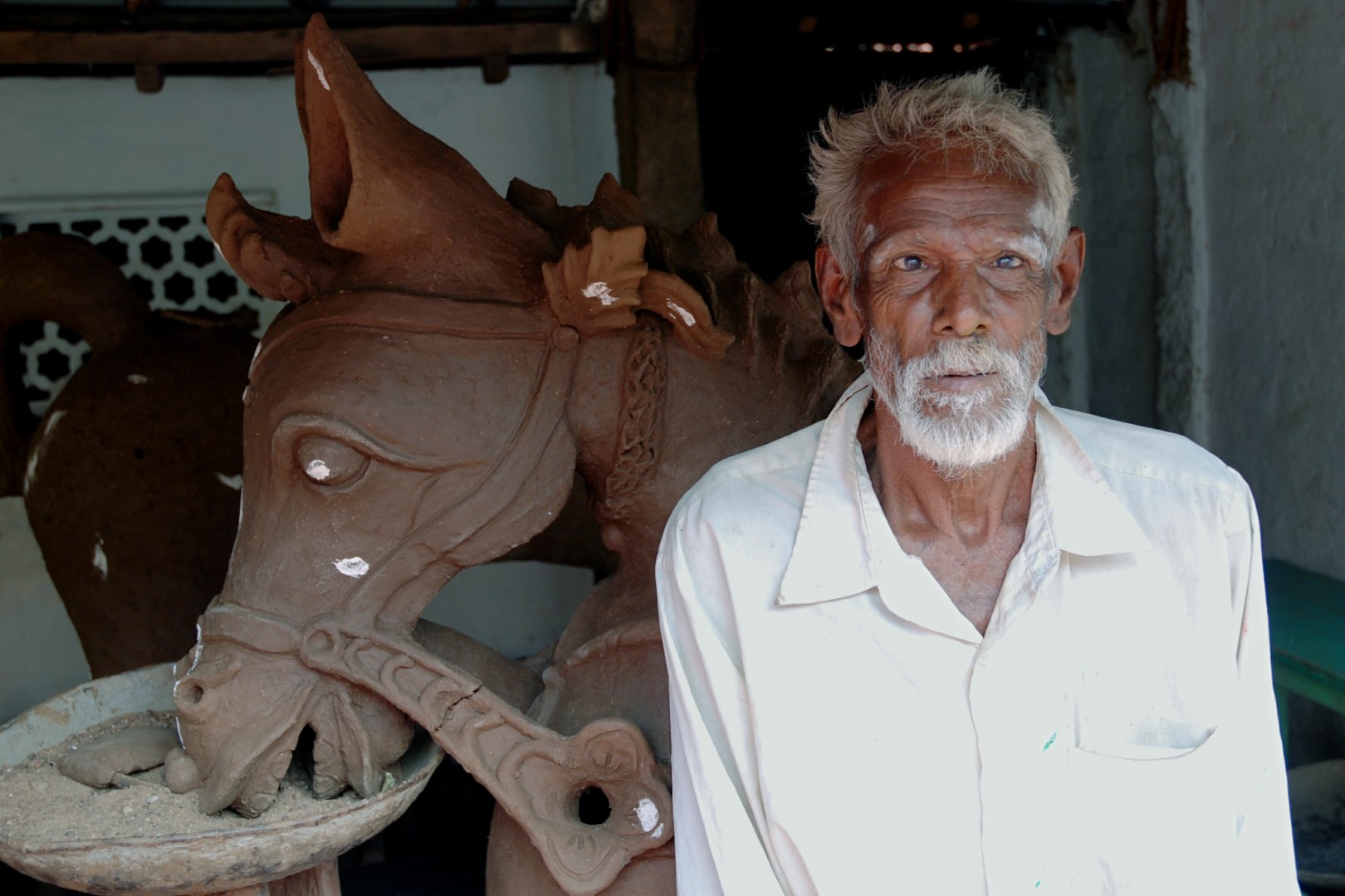 <span style="font-weight:normal;">An old potter sitting beside the horse's head he has created. To keep it steady while it is drying, the head is balanced in a dish of sand.</span>