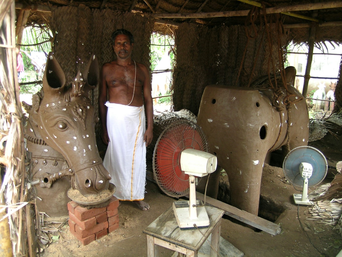 <span style="font-weight:normal;">Palaniappan is the chief potter for the festival in Thekkur and is responsible for the creation of the <i>ure-kutherai</i>.The village horse, made in two parts, will be close to four-metres high when assembled. Because of intermittent summer showers, Palaniappan has put fans in his workshop and keeps them whirring all day for one week, to insure that the clay is sufficiently dry before the pieces are fired.</span>