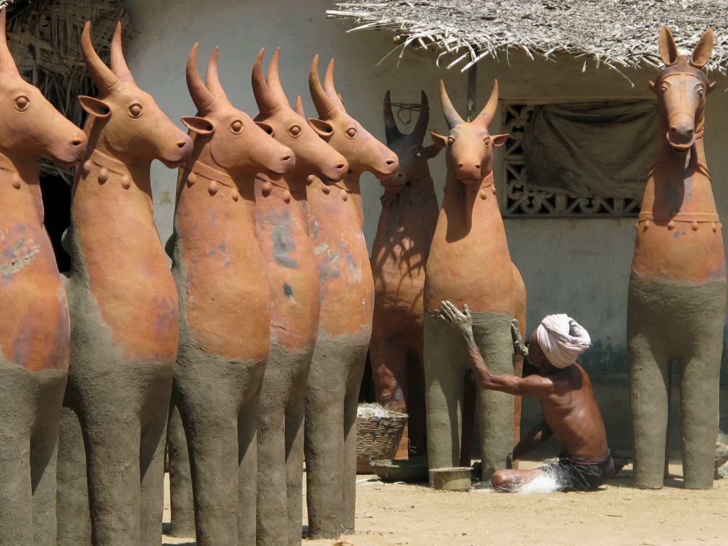 <span style="font-weight:normal;">The legs and bodies of a line of freshly baked offerings are given their final caress with mud made from earth, cow dung, rice hulls and some millet flour. Small handfuls of banana fibre are patted into the mud and finally the reinforced pieces are left to dry before they are painted.</span>