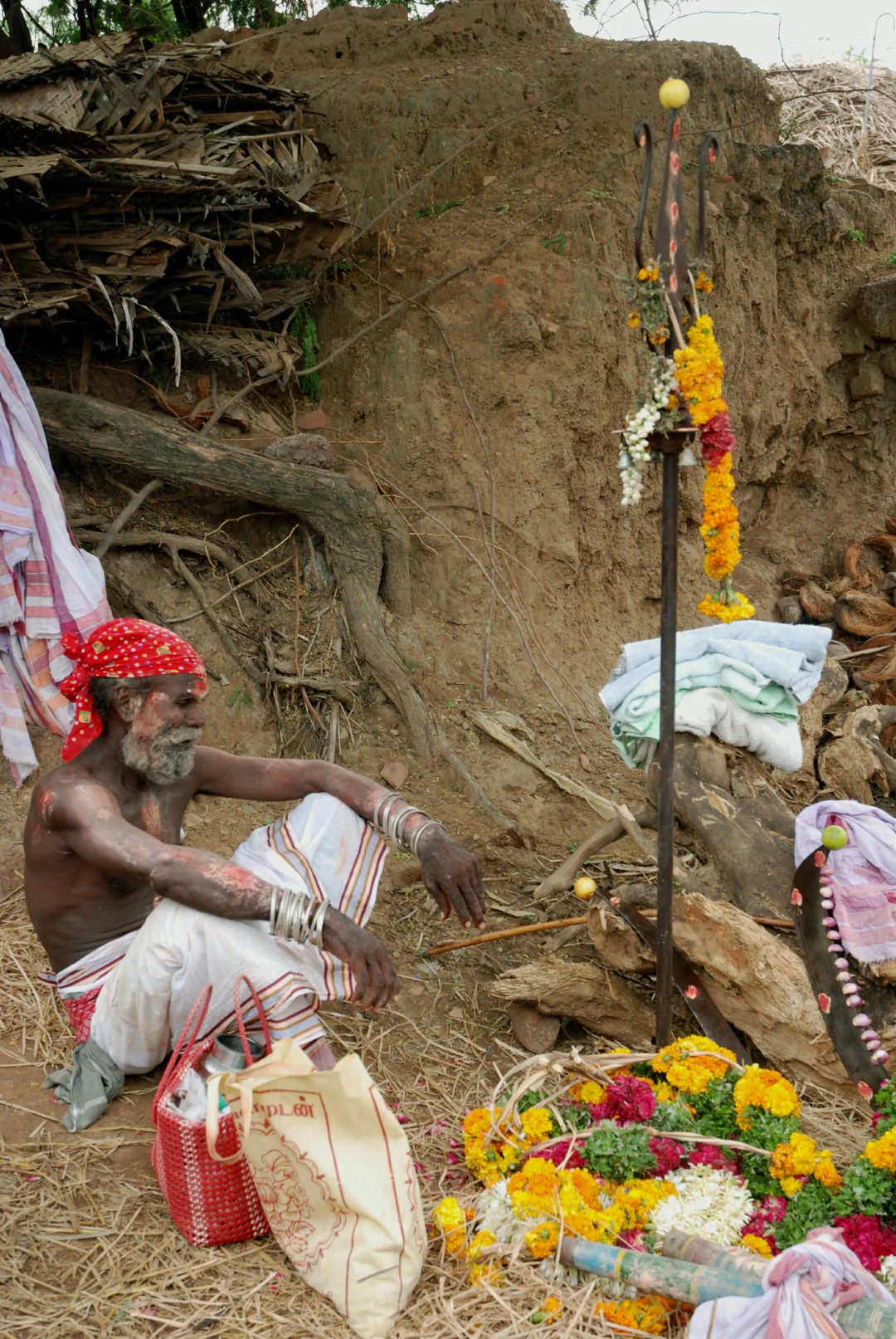 <span style="font-weight:normal;">A <i>sami-adi</i> waiting for the rituals to begin, sits next to a sacred trident and flower garlands. The silver bracelets he is wearing are traditional and common elements of his station.</span>