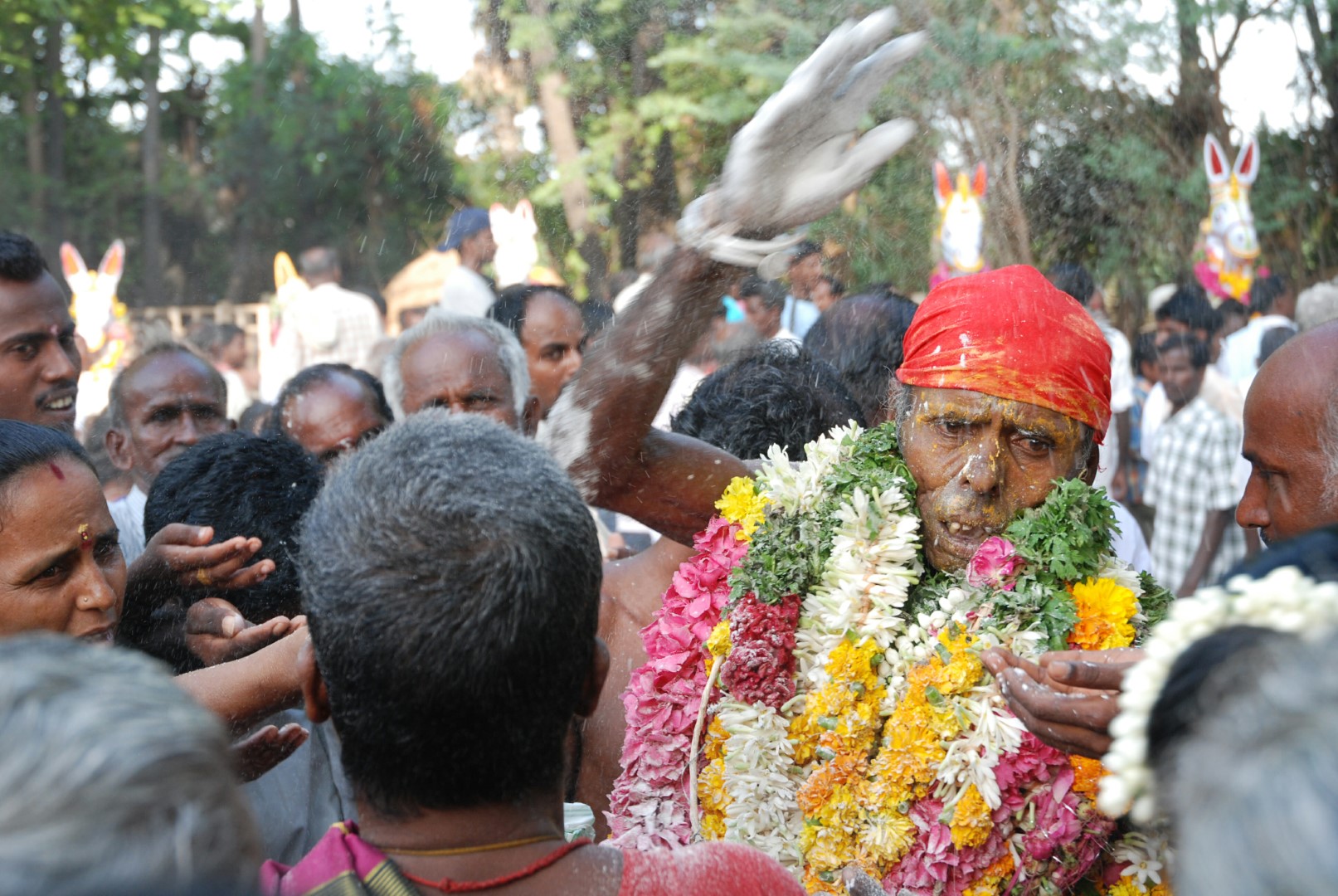 <span style="font-weight:normal;"><i>Sami</i> blesses one of his devotees by slapping her on the head with <i>vibhuti</i>, while other devotees hold out their hand to receive the sacred ashes as a benediction from god.</span>