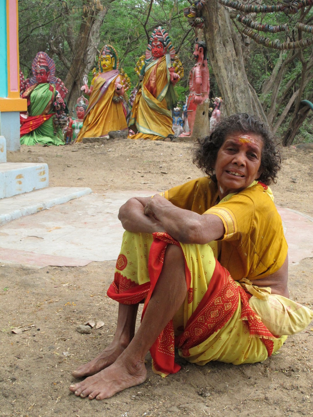 <span style="font-weight:normal;">A devotee sits outside a small Muthurakash shrine where women are not permitted to enter. The grounds surrounding the enclosed shrine are crowded with effigies of the Tamil goddess Kaliyamman who has been lavished with bangles and silk saris.</span>