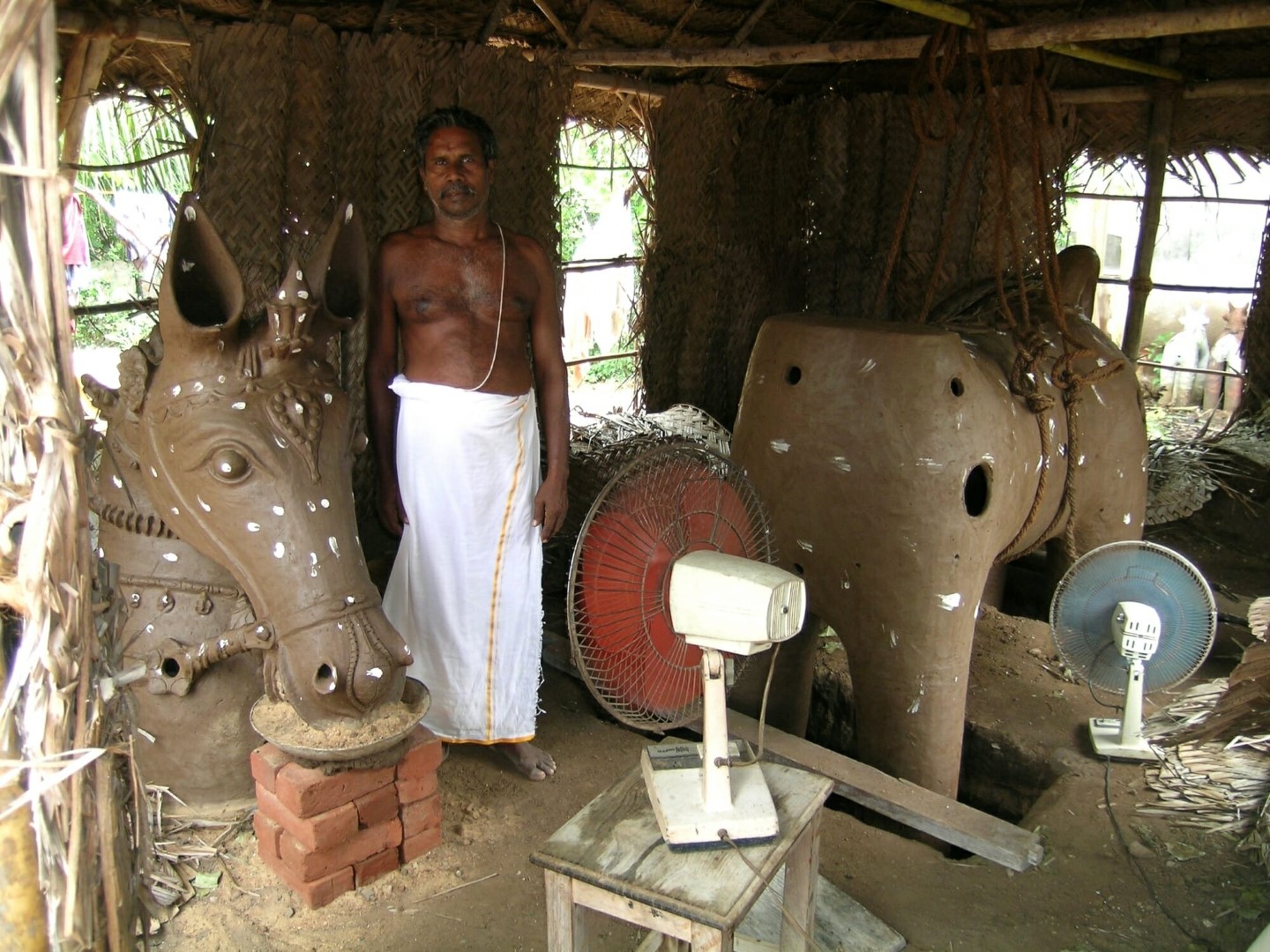 <span style="font-weight:normal;">Palaniappan is the chief potter for the festival in Thekkur and is responsible for the creation of the <i>ure-kutherai</i>. The village horse, made in two parts, will be close to four-metres high when assembled. Because of intermittent summer showers, Palaniappan has put fans in his workshop and keeps them whirring all day for one week, to insure that the clay is sufficiently dry before the pieces are fired.</span>